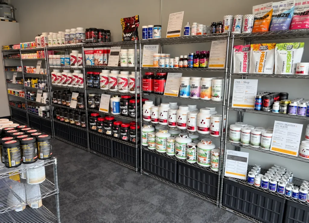 Supplement shelves in the shop: protein tubs, electrolyte bags, vitamins and greens